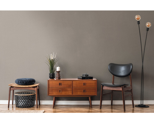 Wohnzimmer mit Holzkommode, Stuhl, Hocker und Stehlampe