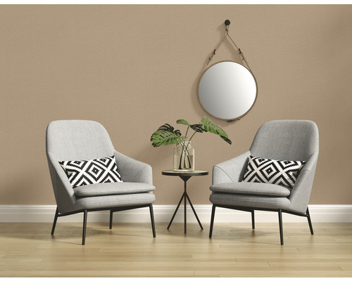 Zwei graue Sessel mit Kissen, ein Beistelltisch mit einer Vase und einer Pflanze, sowie ein runder Spiegel vor einer Wand.