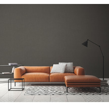 Salon moderne avec canapé marron, tapis à motif géométrique et lampadaire.