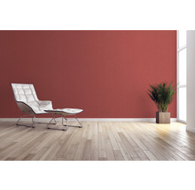 Wohnzimmer mit Sessel, Fußhocker, Zimmerpflanze und Wandgestaltung