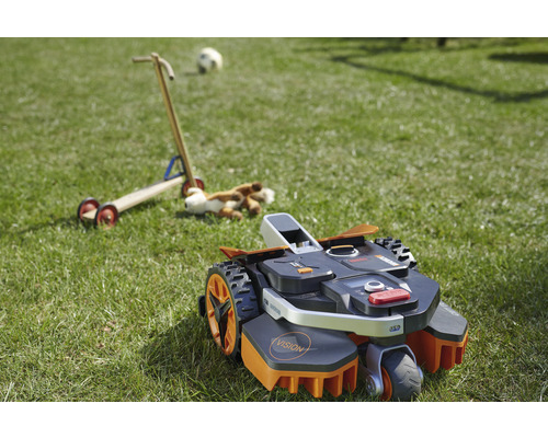 Rasenroboter auf einer Rasenfläche mit Spielzeug im Hintergrund