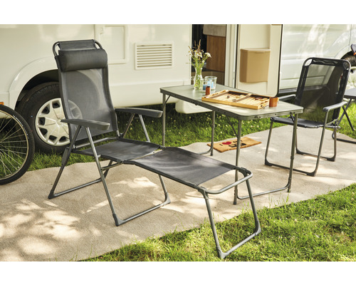 Campingplatzszene mit Liegestuhl, Stuhl und Tisch vor einem Wohnwagen