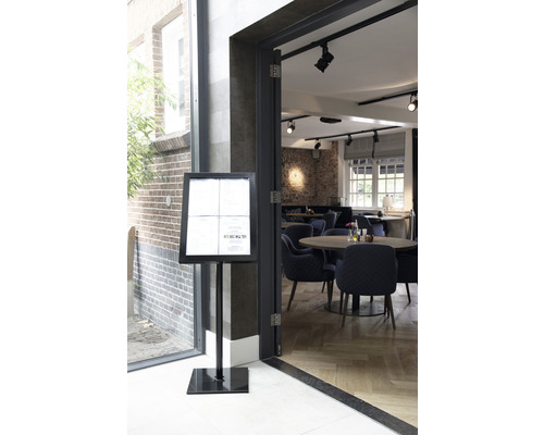 Restaurantansicht mit Menütafel am Eingang und Tischen im Hintergrund.