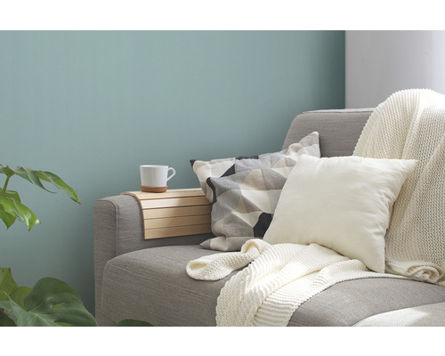 Dekoratives Wohnzimmer mit Sofa, Kissen, Überwurf, Holzablage und Tasse