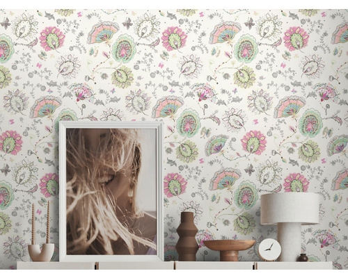 Wohnraum mit Blumentapete, Kommode, Tischlampe, Uhr und Dekoration