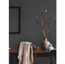 Dekoratives Interieur mit Tisch, Stuhl, Vase, Zweigen und Textilien.