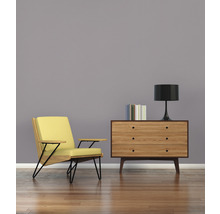 Wohnzimmer mit Sessel, Kommode, Lampe und Büchern auf Holzboden