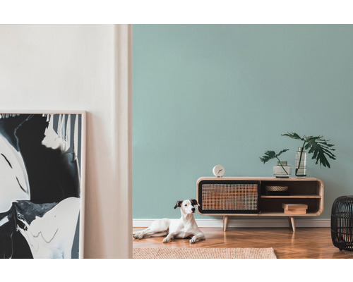 Wohnzimmer mit Sideboard aus Holz, Tischuhr, Zimmerpflanzen, abstrakter Kunst und Hund