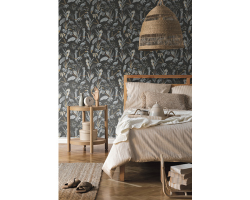 Schlafzimmer mit Bett vor einer gemusterten Dschungeltapete mit Pflanzen- und Vogelmotiven