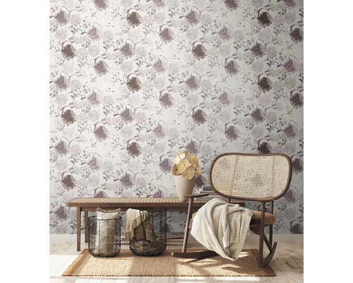 Gemütlicher Wohnbereich mit Blumentapete, Holzbank, Korbstuhl, Teppich und Dekorationsgegenständen.