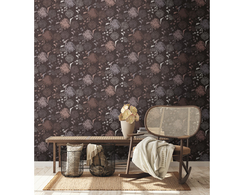 Innenraum mit dunkler, gemusterter Tapete, Holzbank, Korbsessel und Dekorationen