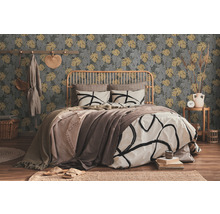 Schlafzimmer mit Bett vor einer gemusterten Tapete mit Pflanzenmotiven.
