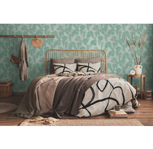 Helles Schlafzimmer mit Bett vor einer grünen Tapete mit Blättern