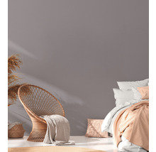 Heller Raum mit Rattansessel, Bett und Dekoration für ein gemütliches Ambiente.
