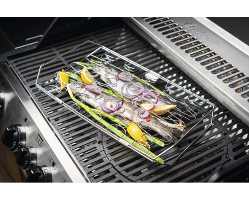 Fisch im Grillkorb auf einem Gasgrill mit Zitrone, Zwiebeln und Lauchzwiebeln