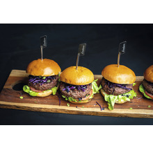 Mehrere Burger mit Fleisch, Salat und Enders Fähnchen auf einem Holzbrett
