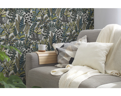 Salon avec canapé, coussins, couverture et papier peint floral