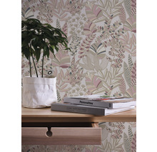 Dekoratives Zimmer mit Blumentapete, Pflanze und Büchern auf einem Tisch.
