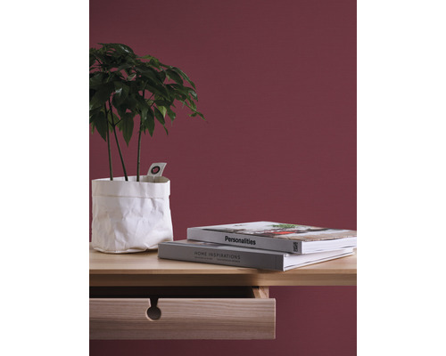 Dekoratives Arrangement mit Zimmerpflanze in Papierhülle, Büchern und Holzschreibtisch