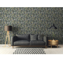 Wohnzimmer mit gemusterter Blättertapete, Sofa, Stehlampe, Teppich und Beistelltisch.