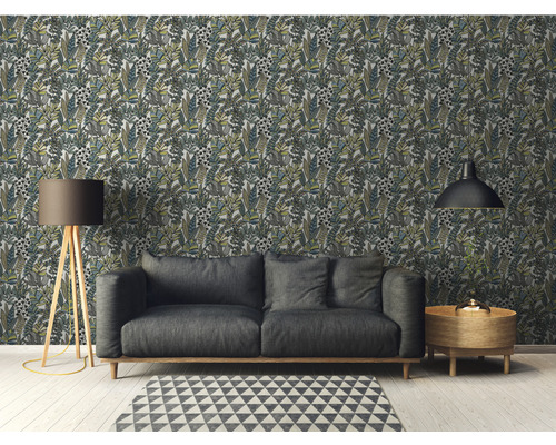 Salon avec papier peint à motifs de feuilles, canapé, lampadaire, tapis et table d''appoint.