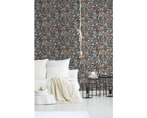 Schlafzimmer mit floral gemusterter Tapete, Bett und Beistelltischen.