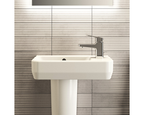 Waschtisch mit Armatur und Säule vor gefliester Wand