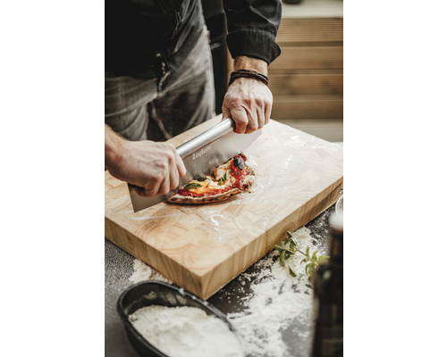 Eine Person schneidet Pizza auf einem Holzbrett mit einem Pizzaschneider.