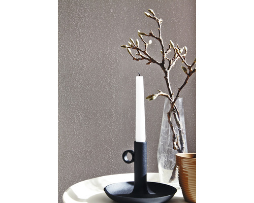 Gros plan d''un mur avec enduit décoratif, d''un bougeoir avec une bougie et d''un vase en verre avec des branches.