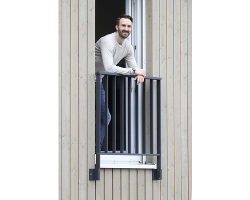 Un homme s''appuie sur une grille de fenêtre sur une maison en bois