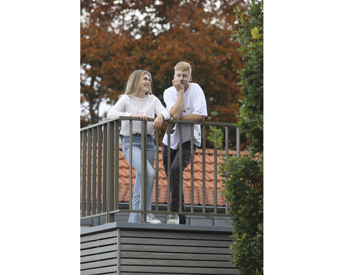 Zwei Personen stehen auf einem Balkon mit Metallgeländer und Holzboden.