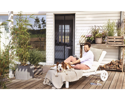 Mann entspannt mit Hund auf einer Liege auf der Terrasse mit Insektenschutzgittertür