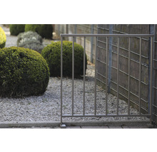Metallzaun im Garten mit Kies und Büschen