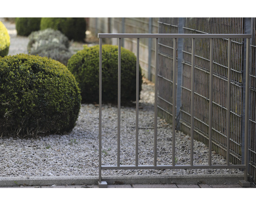 Clôture métallique dans un jardin avec sol en gravier et arbustes