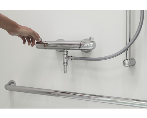 Main actionnant un robinet de douche dans une salle de bains