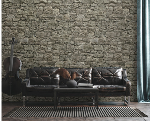 Salon avec mur en pierre, canapé en cuir et violoncelle