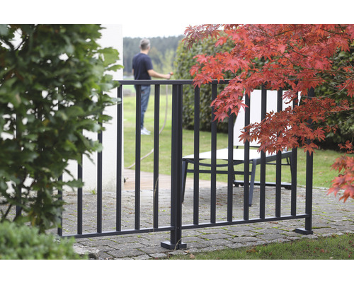 Zaun aus Metall im Aussenbereich mit Gartenmöbeln und Laubbaum