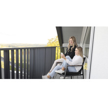 Deux femmes sont assises sur un balcon avec une balustrade et profitent de la vue.