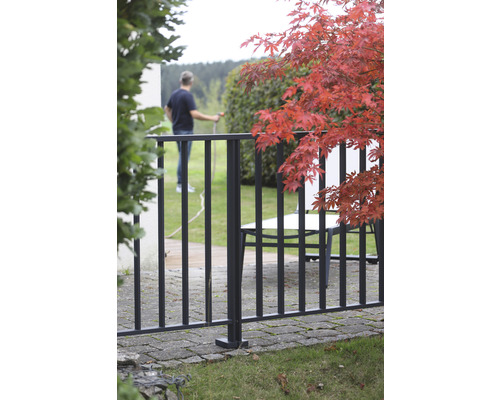 Garten mit Metallzaun, Tisch und Person mit Wasserschlauch