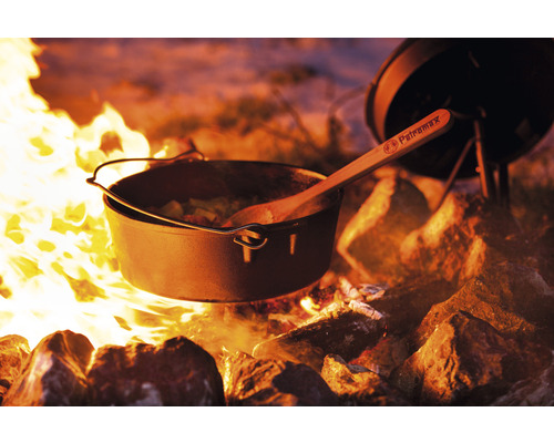 Gusseiserner Dutch Oven mit Holzkochlöffel über offenem Feuer