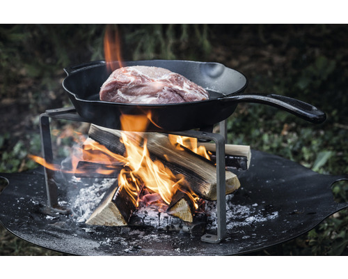 Fleisch in Bratpfanne über offenem Feuer auf Feuerstelle