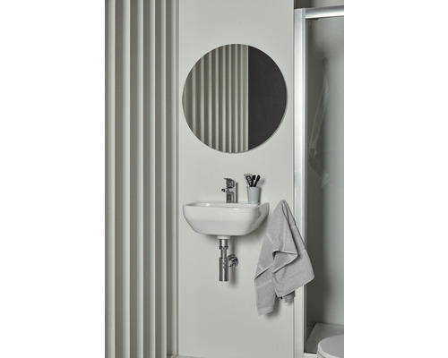 Lavabo de salle de bain avec miroir rond, robinet, serviette et accessoires