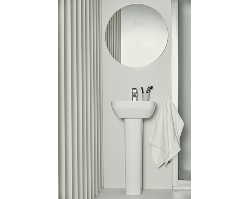 Scène de salle de bains avec lavabo, miroir rond et serviette