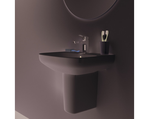 Waschbecken mit Armatur, Seife, Zahnbürste und Becher im Badezimmer