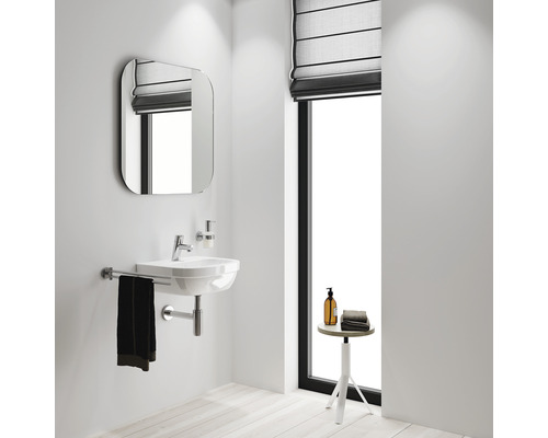 Salle de bain lumineuse avec lavabo, miroir et fenêtre.