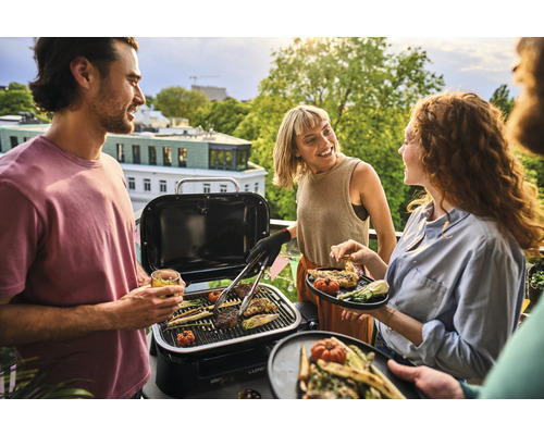 Des personnes font des grillades avec un barbecue portable sur un balcon