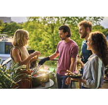 Gruppe von Freunden grillt auf dem Balkon mit einem Tischgrill und genießt die Zeit.