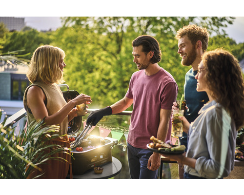 Groupe d''amis faisant des grillades sur le balcon avec un barbecue de table et profitant du moment.
