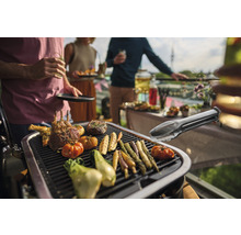 Grillszene mit Fleisch, Gemüse und Grillzange auf einem Grill bei einer Gartenparty