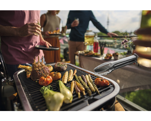 Scène de barbecue avec de la viande, des légumes et une pince à gril sur un barbecue lors d''une garden-party
